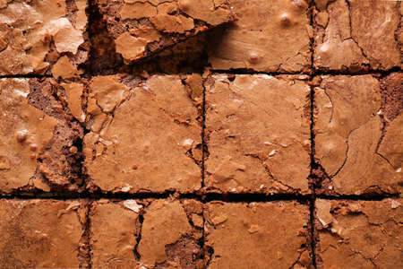 Cut chocolate brownie as background, closeup
