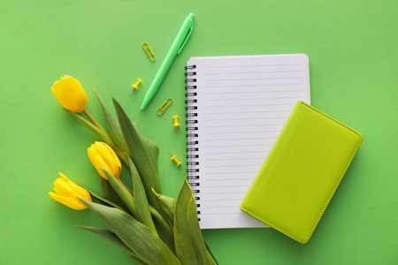Composition with notebooks and yellow tulips on green backgroundの写真素材