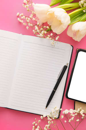 Open notebook, pen and flowers on color background, closeup