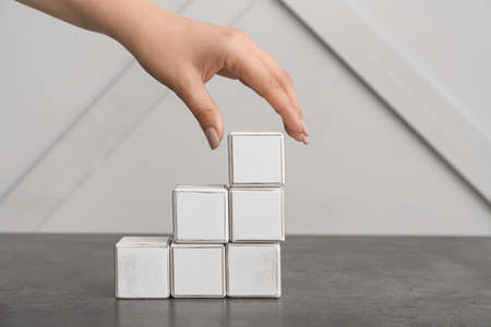 Female hand with cubes on gray background. concept of progress