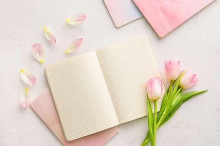 Composition with notebooks and beautiful tulips on light backgroundの写真素材