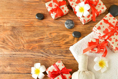 Spa stones, herbal bag, towel and gift boxes on wooden background. Valentine's Day celebrationの写真素材