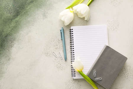 Composition with notebooks, pen and tulips on light backgroundの写真素材