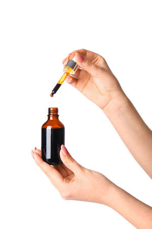 Female hands with bottle and pipette of iodine on white backgroundの写真素材