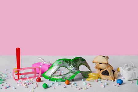 Carnival mask and Hamantaschen cookies with rattle and gifts for Purim holiday on color backgroundの写真素材