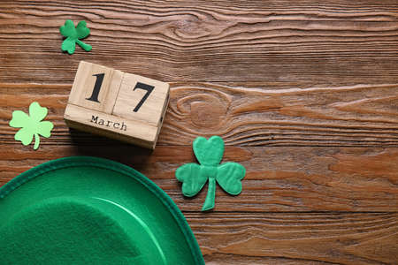 Leprechaun hat and calendar with date of St. Patrick's Day on wooden background