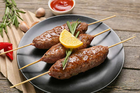 Plate of skewers with tasty lula kebab on wooden background