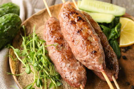 Plate of skewers with tasty lula kebab on table, closeup