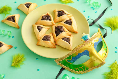 Carnival mask and Hamantaschen cookies for Purim holiday on color backgroundの写真素材