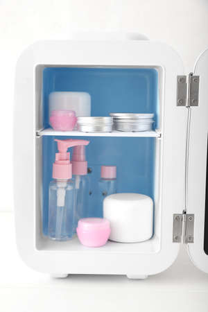 Small refrigerator with cosmetic products on light tableの写真素材