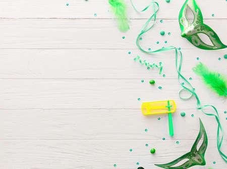 Carnival masks and rattle for Purim holiday with party decor on white wooden backgroundの写真素材