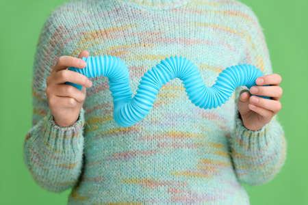 Little girl with blue Pop Tube on green background, closeupの写真素材
