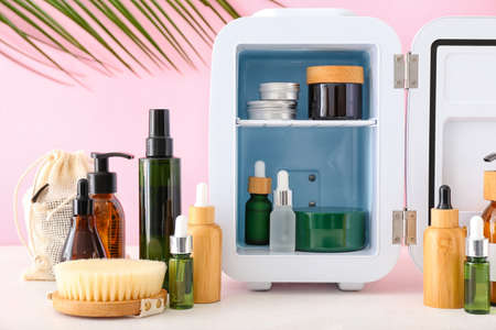 Small refrigerator with cosmetic products on light table