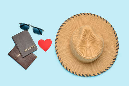 Passports with paper heart, sunglasses and hat on blue background. Valentine's Day celebration