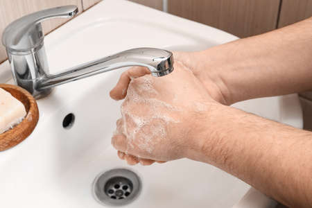 Man washing his hands with liquid soap near sink in bathroom, closeup
