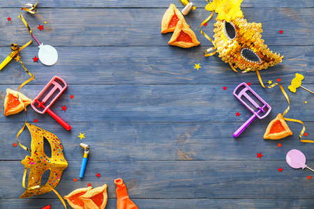 Carnival masks and Hamantaschen cookies with rattles for Purim holiday on color wooden backgroundの写真素材