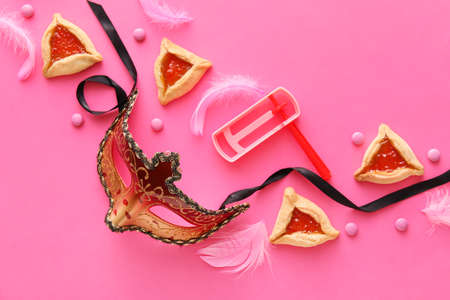 Carnival mask and Hamantaschen cookies with rattle for Purim holiday on color backgroundの写真素材