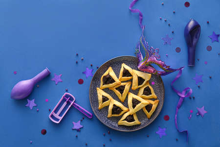 Carnival mask and Hamantaschen cookies with rattle for Purim holiday on color backgroundの写真素材