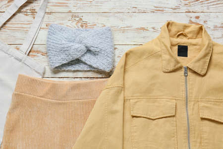 Female jacket, skirt, bag and headband on light wooden background