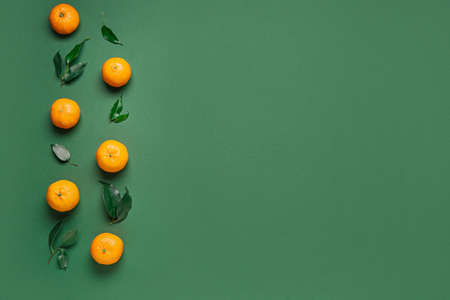 Ripe tangerines and leaves on green backgroundの写真素材