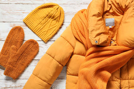 Winter jacket, hat, mittens and scarf on light wooden backgroundの写真素材