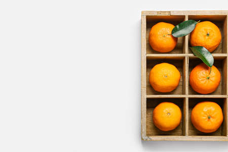 Wooden box with ripe tangerines on white backgroundの写真素材