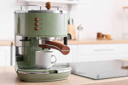 Modern coffee machine with cup on counter in kitchenの写真素材