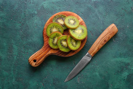 Wooden board with slices of fresh kiwi on green backgroundの写真素材