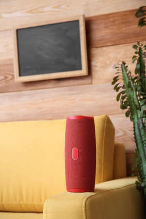 Wireless portable speaker on armchair near wooden wallの写真素材