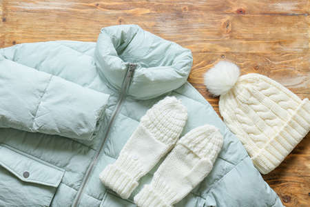 Winter jacket, mittens and hat on wooden backgroundの写真素材