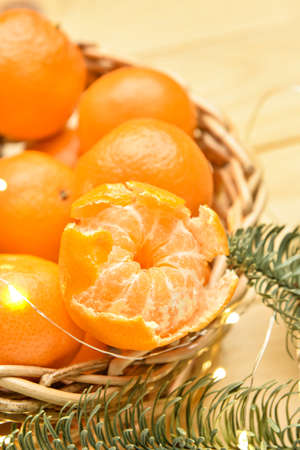 Wicker bowl with tasty tangerines and Christmas lights on table, closeupの写真素材