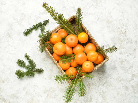 Box with tasty tangerines and fir branches on light backgroundの写真素材