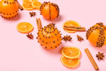 Handmade Christmas decoration made of tangerines with cloves on pink background, closeupの写真素材