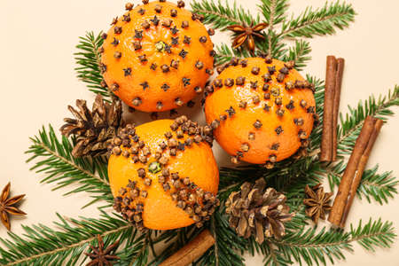 Handmade Christmas decoration made of tangerines with cloves and fir branches on beige background, closeupの写真素材