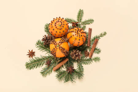 Handmade Christmas decoration made of tangerines with cloves and fir branches on beige backgroundの写真素材