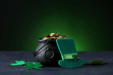 Pot with coins and leprechaun's hat on table against dark background. St. Patrick's Day celebration