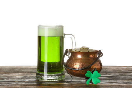 Glass of beer and pot with coins on table against white background background. St. Patrick's Day...