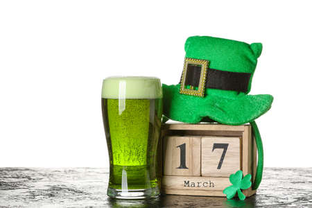 Leprechaun's hat, calendar and glass of beer on table against white background. St. Patrick's Day...