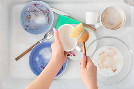 Woman with brush cleaning cup over ceramic sink, closeupの写真素材