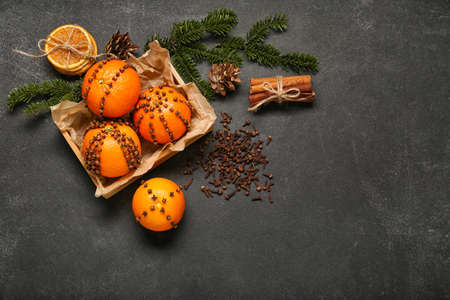 Handmade Christmas decoration made of tangerines with cloves and fir branches on dark backgroundの写真素材