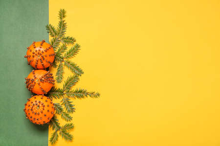 Handmade Christmas decoration made of tangerines with cloves and fir branches on color background