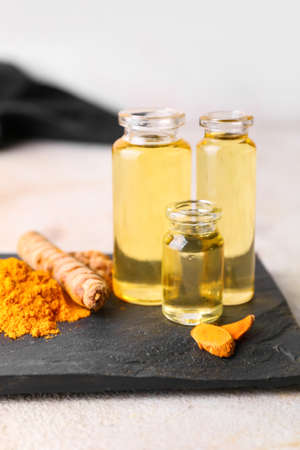 Bottles of oil, turmeric root and powder on light background