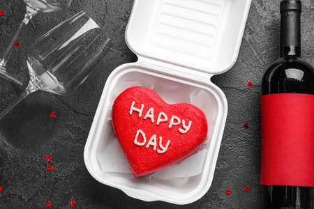 Composition with tasty bento cake, bottle of wine and glasses on dark backgroundの写真素材