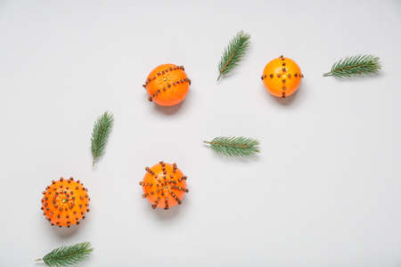 Handmade Christmas decoration made of tangerines with cloves and fir branches on light backgroundの写真素材