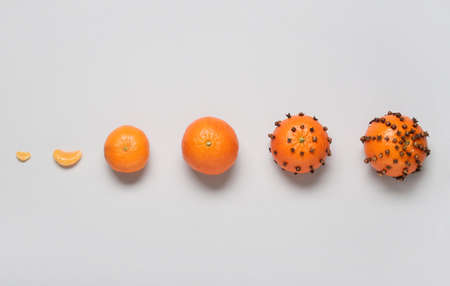 Handmade Christmas decoration made of tangerines with cloves on gray background