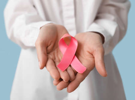 Young woman with pink ribbon on blue background, closeup. breast cancer awareness conceptの写真素材