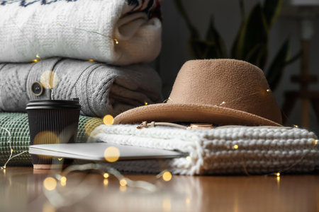 Knitted sweaters, felt hat, paper cup and glowing lights, closeupの写真素材