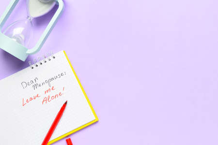 Notebook with text DEAR MENOPAUSE LEAVE ME ALONE and hourglass on lilac backgroundの写真素材