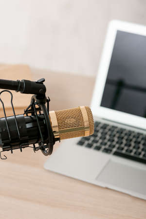 Broadcaster's workplace with modern laptop and professional microphone, closeup