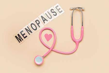 Word MENOPAUSE with stethoscope and paper heart on beige backgroundの写真素材
